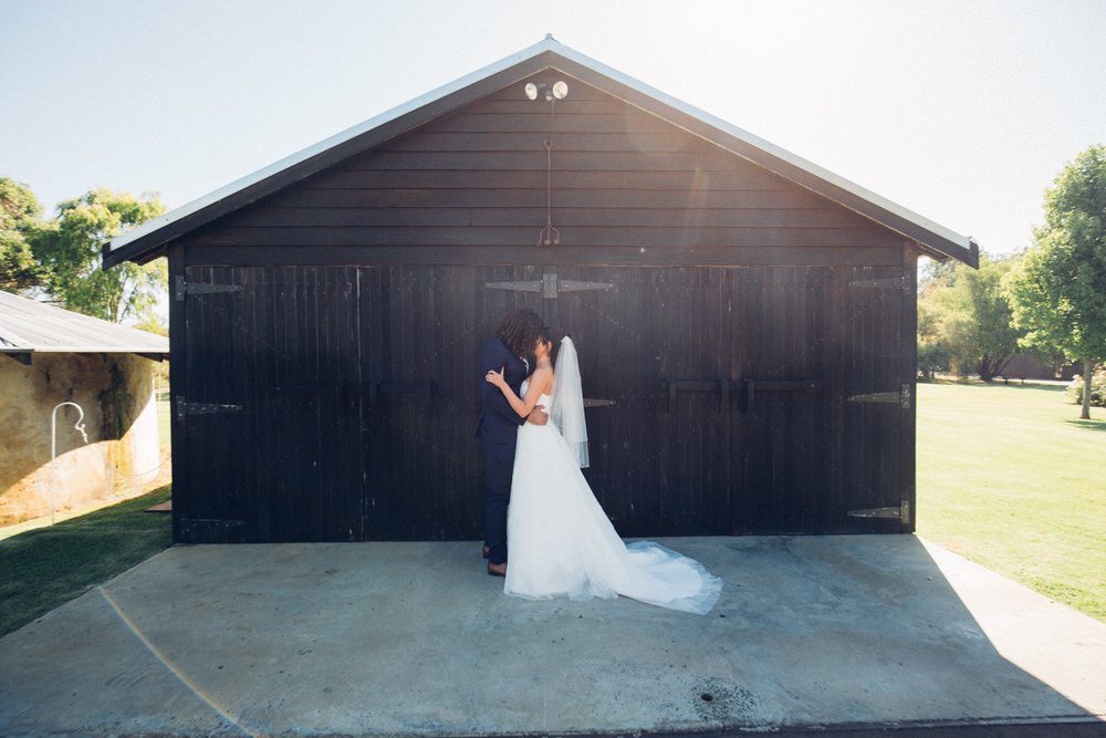 bride and groom kissing infront of rustic barn