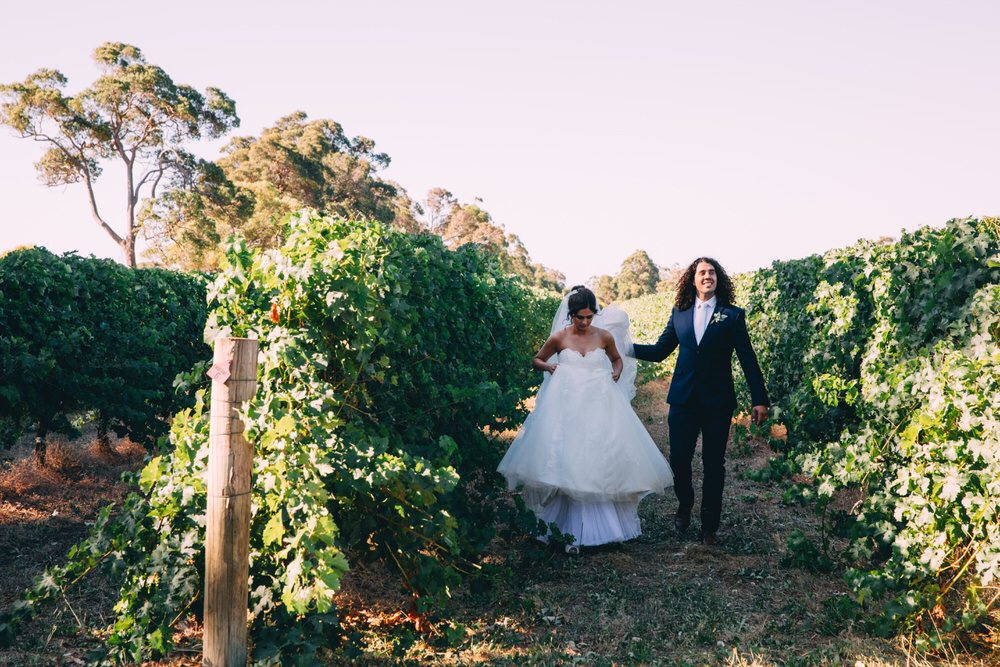 bride and groom walking in a vinyard