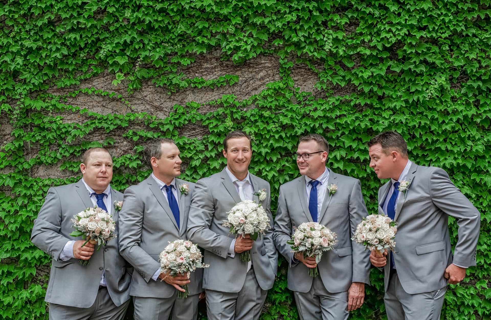 funny photo of the groom & groomsmen holding wedding flowers
