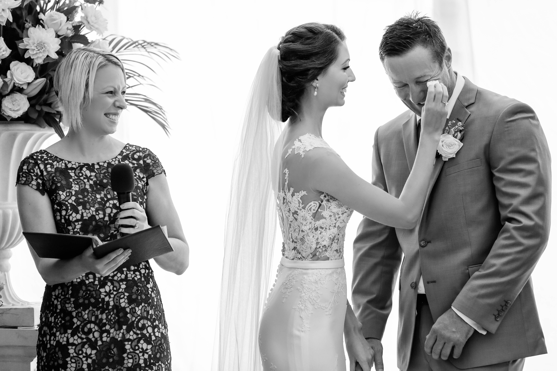 bride wiping tears from the groom while celebrant smiles