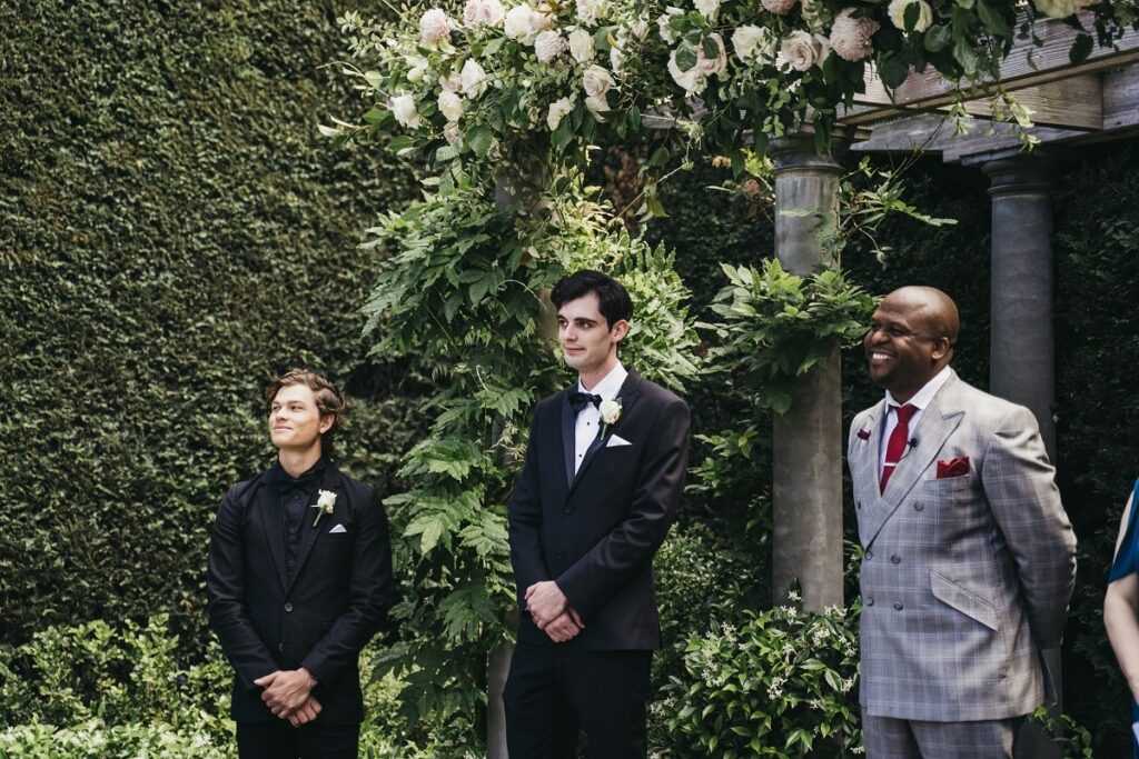 Kyle, together with his best man and wedding officiant, waits at the altar