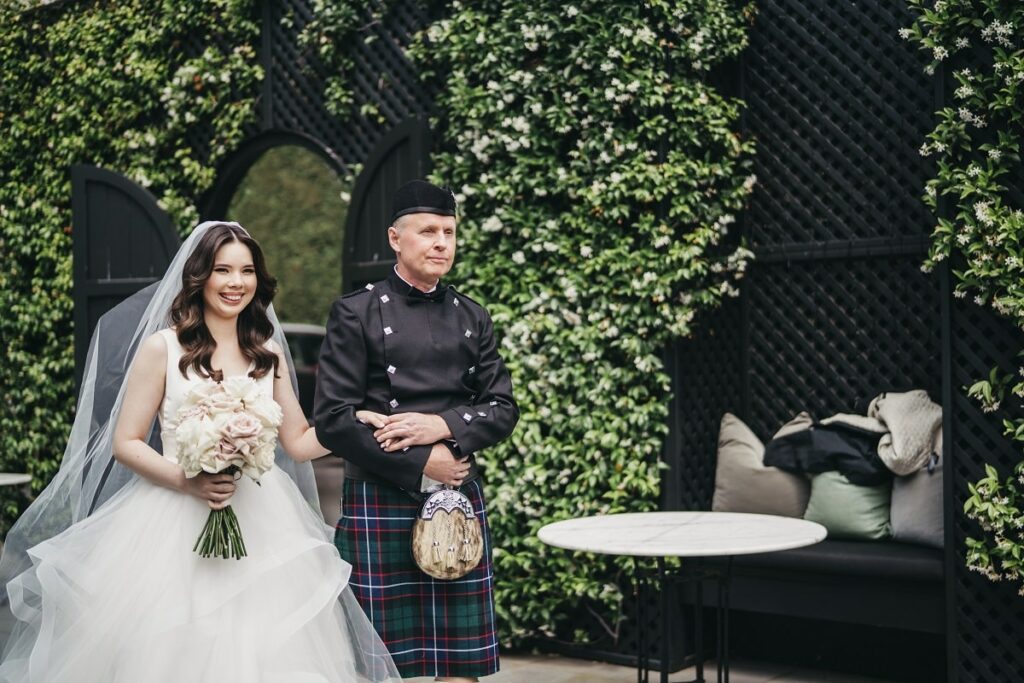 Sophia walking down the aisle with her father wearing their family's Scottish traditional Russell clan's kilt