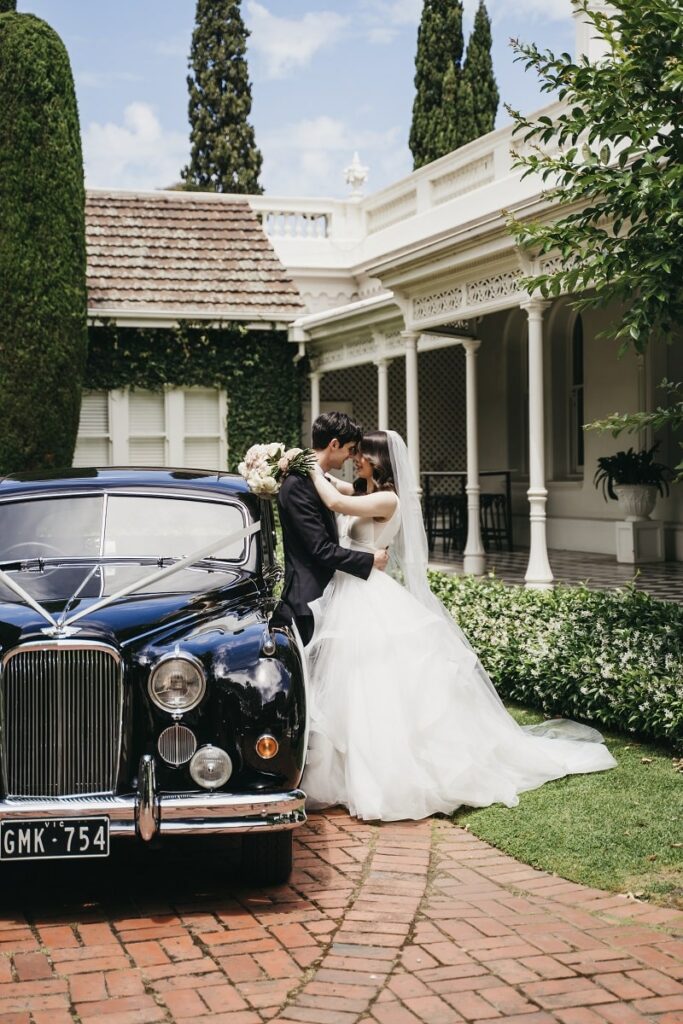 Couple's photo next to their stunning 1955 Jaguar MKVII sedan bridal car